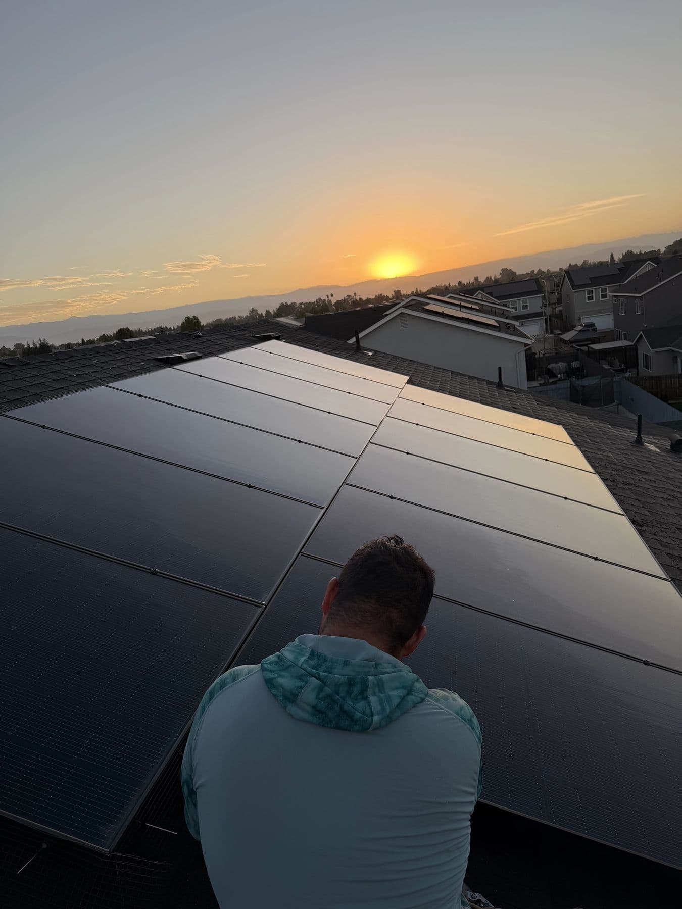 Ramos Power Wash crew member on a rooftop solar array at sunset